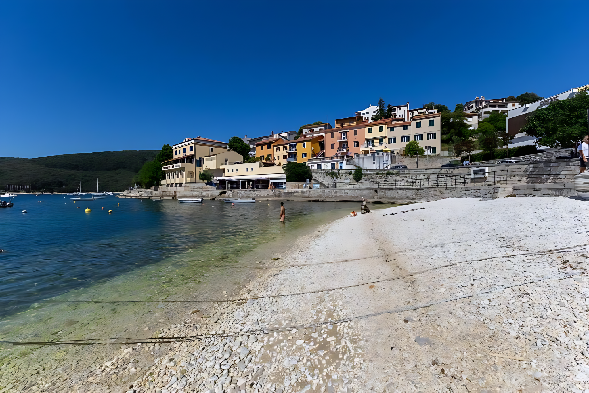 Waterfront houses and the promenade seen from the beach in Rabac